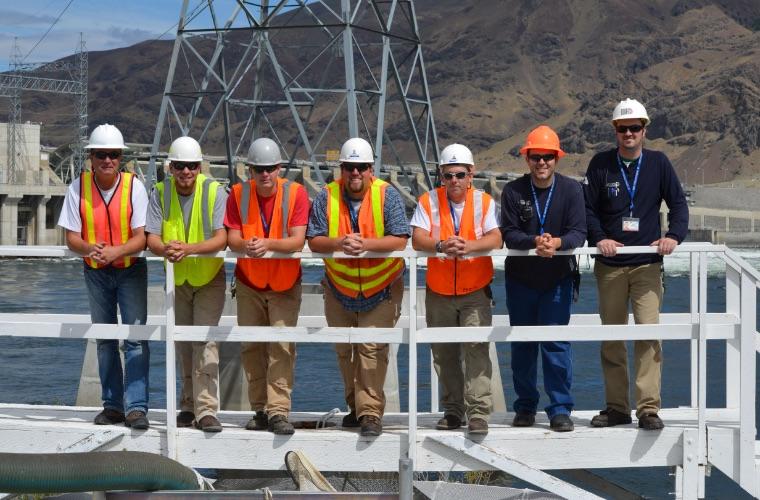 Group of Grant PUD employees standing near dam railing
